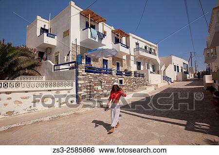 Stock Photograph - Woman walking in the town center in front of typical cyclades houses, Koufonissi, Cyclades Islands, Greek Islands, Greece, Europe.. Fotosearch