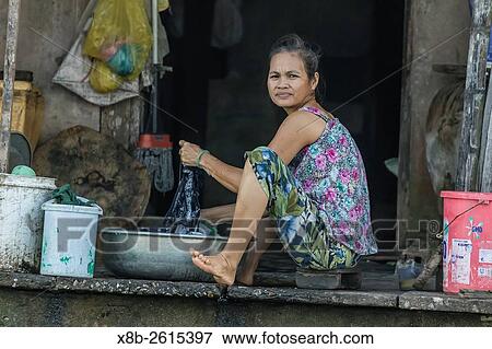 Stock Photo - Women washing dishes and clothes on the Mekong River Delta at Cai Be, Vietnam.. Fotosearch