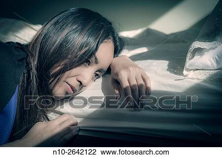 Stock Image - Young Asian woman by her bed.. Fotosearch
