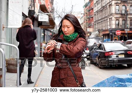 Young Asian woman urgently checks her watch in the streets of Manhattan, New York, NY, USA. View Large Photo Image Stock Image - Young Asian woman urgently checks her watch in the streets of Manhattan, New York, NY, USA.. Fotosearch
