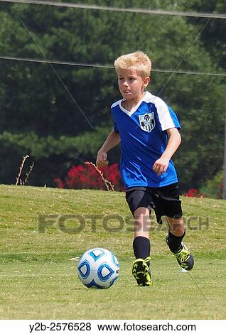Young boy playing soccer wearing blue jersey. View Large Photo Image Stock Photo - Young boy playing soccer wearing blue jersey.. Fotosearch