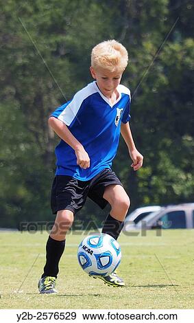 Stock Photo - Young boy playing soccer wearing blue jersey.. Fotosearch