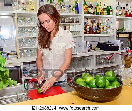 Young female bartender cutting limes, preparing cocktails. Woman barman at work. View Large Photo Image Picture - Young female bartender cutting limes, preparing cocktails. Woman barman at work.. Fotosearch