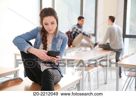 Young female student with smartphone at classroom View Large Photo Image Stock Photo - Young female student with smartphone at classroom. Fotosearch