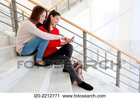 Stock Image - Young female students with digital tablet at campus. Fotosearch