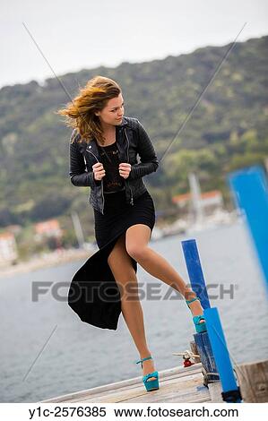 Stock Photography - Young lady in Black dress fights strong wind. Fotosearch