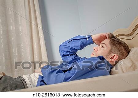 Young man, dress shirt unbuttoned, lying on his bed. View Large Photo Image Stock Photo - Young man, dress shirt unbuttoned, lying on his bed.. Fotosearch