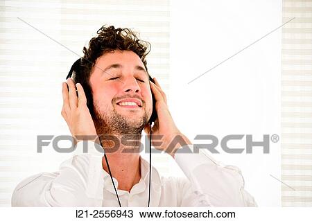 Young man listening to music on his headphones in the interior of a house. View Large Photo Image Stock Image - Young man listening to music on his headphones in the interior of a house.. Fotosearch