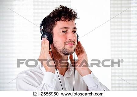 Young man listening to music on his headphones in the interior of a house. View Large Photo Image Stock Image - Young man listening to music on his headphones in the interior of a house.. Fotosearch