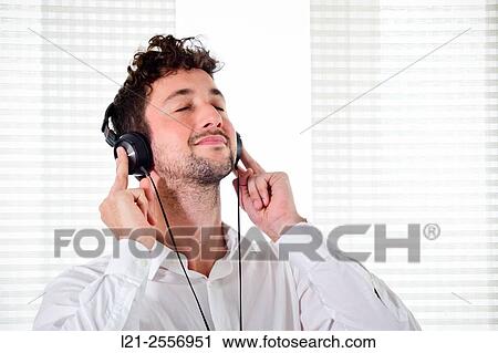 Young man listening to music on his headphones in the interior of a house. View Large Photo Image Stock Image - Young man listening to music on his headphones in the interior of a house.. Fotosearch