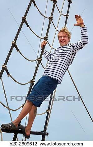 Stock Image - Young man man on the outside of a sailboat, galleon. Masts. Scale. Basque Country. Spain. Fotosearch