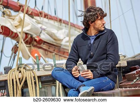 Stock Image - Young man on the outside of a sailboat, galleon. Masts. Basque Country. Spain. Fotosearch