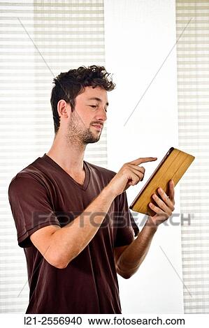 Young man using a tablet inside a house. View Large Photo Image Stock Image - Young man using a tablet inside a house.. Fotosearch