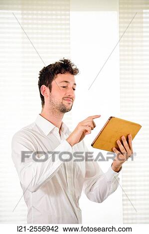 Young man using a tablet inside a house. View Large Photo Image Stock Image - Young man using a tablet inside a house.. Fotosearch