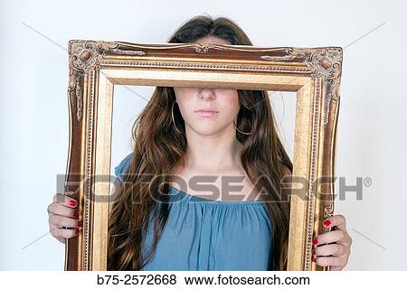Young teen with long brown hair, with a gilded frame in hands covering her eyes. View Large Photo Image Stock Photo - Young teen with long brown hair, with a gilded frame in hands covering her eyes.. Fotosearch
