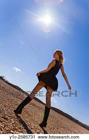 Stock Image - Young woman against glaring sun. Fotosearch