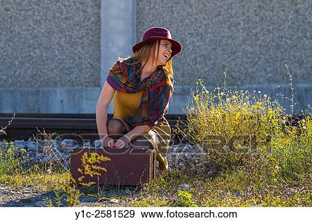 Stock Photo - Young woman dressed old-fashioned is waiting for transport. Fotosearch