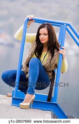 Stock Image - Young woman framed by metal fence. Fotosearch
