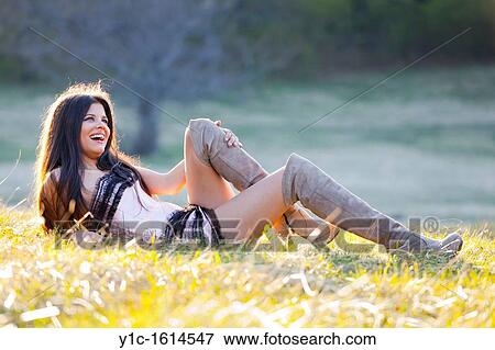 Stock Photo - Young woman in the grass laughing loudly. Fotosearch