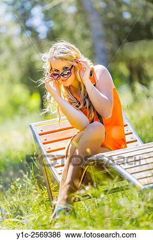 Young woman is flirting peeking over sunglasses View Large Photo Image Stock Photograph - Young woman is flirting peeking over sunglasses. Fotosearch