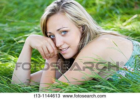 Young woman is lying in grass with a single straw in mouth View Large Photo Image Stock Image - Young woman is lying in grass with a single straw in mouth. Fotosearch