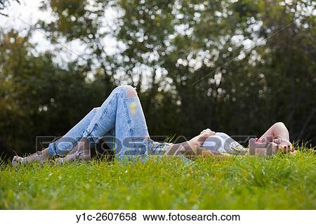 Young woman lying in meadow side-view View Large Photo Image Stock Photo - Young woman lying in meadow side-view. Fotosearch