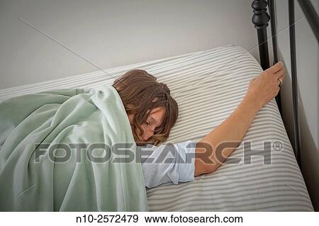 Stock Photo - Young woman lying on her bed.. Fotosearch