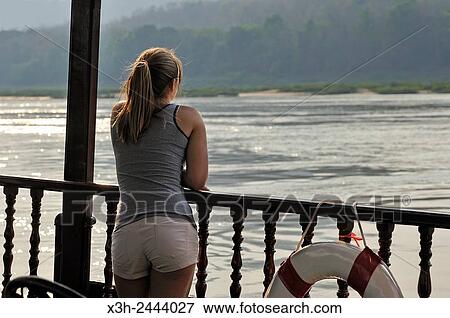 young woman standing at the railing of a cruise boat, owned by?? The Luang Say Lodge & Cruises??, on Mekong River, between Pakbeng and Luang Prabang, Oudomxay Province, Laos, Southeast Asia. View Large Photo Image Stock Photo - young woman standing at the railing of a cruise boat, owned by?? The Luang Say Lodge & Cruises??, on Mekong River, between Pakbeng and Luang Prabang, Oudomxay Province, Laos, Southeast Asia.. Fotosearch