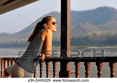 Young Woman Standing At The Railing Of A Cruise Boat Owned By The Luang Say Lodge Cruises On Mekong River Between Pakbeng And Luang Prabang - 