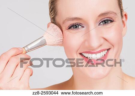 Young woman using blusher brush to apply make up. View Large Photo Image Picture - Young woman using blusher brush to apply make up.. Fotosearch