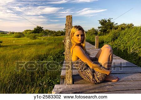 Stock Image - Young woman watching sunset outdoors. Fotosearch