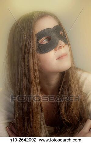 Stock Image - Young woman wearing a black mask.. Fotosearch