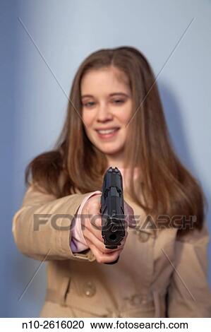 Young woman, wearing a trench coat, holding a gun. View Large Photo Image Stock Image - Young woman, wearing a trench coat, holding a gun.. Fotosearch