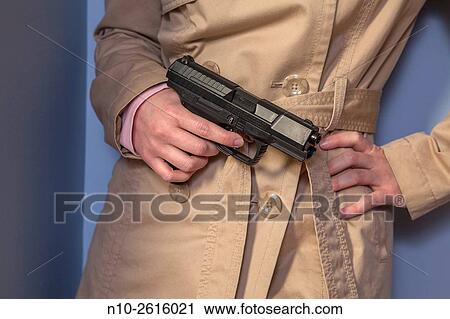 Young woman, wearing a trench coat, holding a gun. View Large Photo Image Stock Image - Young woman, wearing a trench coat, holding a gun.. Fotosearch
