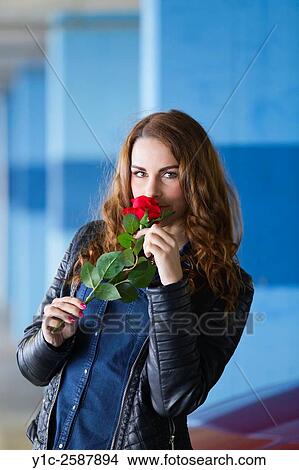 Picture - Young woman with Red rose flower in hands. Fotosearch