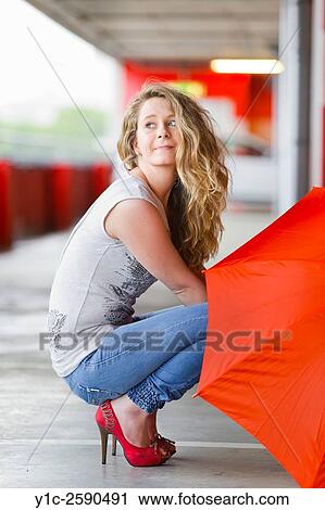 Young woman with Red umbrella squatting View Large Photo Image Stock Image - Young woman with Red umbrella squatting. Fotosearch