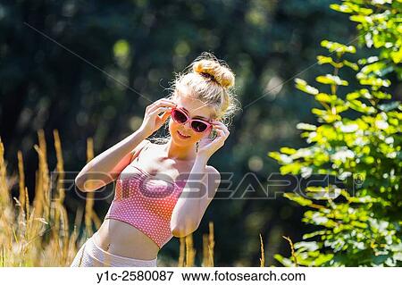 Stock Photo - Young woman with sunglasses in nature under noon-light. Fotosearch