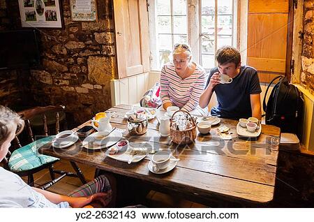 Stock Image - A family enjoy a cream tea at the Plough Inn,. Ford,. Temple Guiting,. Cheltenham, England, Britain, Uk.. Fotosearch