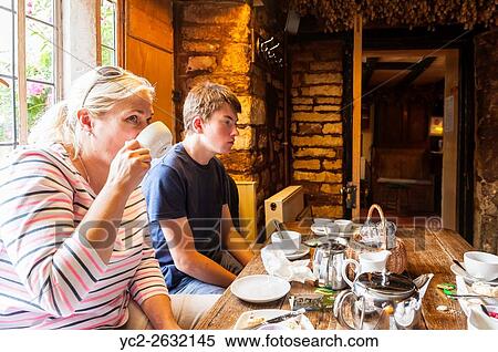 Stock Photography - A family enjoy a cream tea at the Plough Inn,. Ford,. Temple Guiting,. Cheltenham, England, Britain, Uk.. Fotosearch
