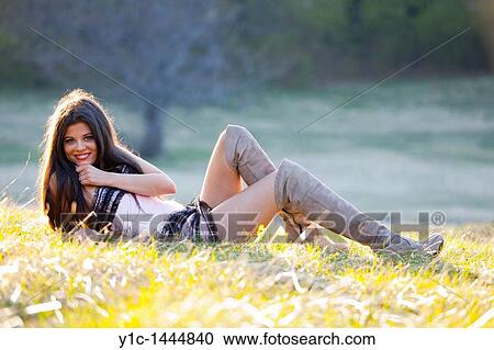 Stock Image - Attractive woman is alluring lying on a grass. Fotosearch