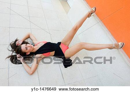 Stock Photo - Attractive woman is posing lying down on the street. Fotosearch