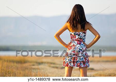 Stock Photo - Attractive young woman from her rear with hands on hips. Fotosearch