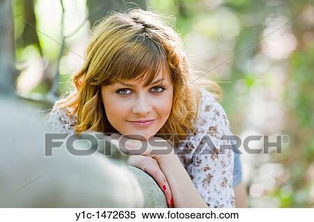 Stock Photography - Attractive young woman is lying on a tree. Fotosearch