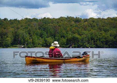 Back view of a man fishing from a small canoe on Limekiln Lake in Old Forge, New York. View Large Photo Image Stock Image - Back view of a man fishing from a small canoe on Limekiln Lake in Old Forge, New York.. Fotosearch