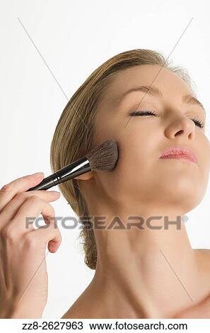 Beautiful young woman applying blusher to her face. View Large Photo Image Stock Image - Beautiful young woman applying blusher to her face.. Fotosearch