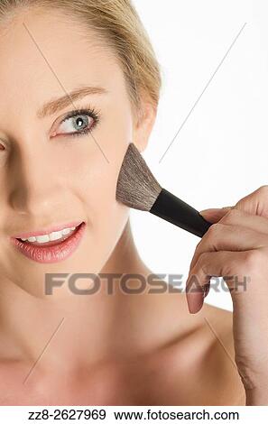 Beautiful young woman applying blusher to her face. View Large Photo Image Stock Photo - Beautiful young woman applying blusher to her face.. Fotosearch