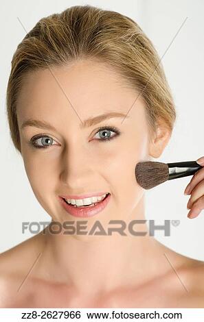 Beautiful young woman applying blusher to her face. View Large Photo Image Stock Photograph - Beautiful young woman applying blusher to her face.. Fotosearch