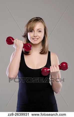 Stock Image - Beautiful young woman working out with dubbells.. Fotosearch