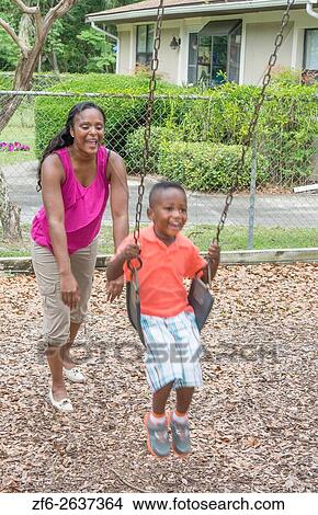 Black single mother swinging her 3 year old son on swings at park having fun together MR-7 MR -10 Model released. View Large Photo Image Picture - Black single mother swinging her 3 year old son on swings at park having fun together MR-7 MR -10 Model released.. Fotosearch