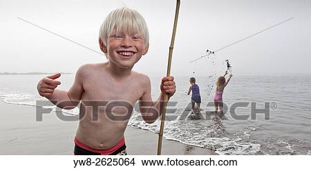 Picture - Boy wih net playing at the beach, Akranes, Iceland.. Fotosearch